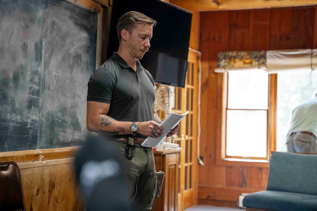 Man in polo shirt reading papers in room
